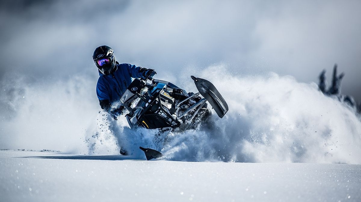 Full Day Snowmobile Rental Image 1 a man riding skis down a snow covered slope